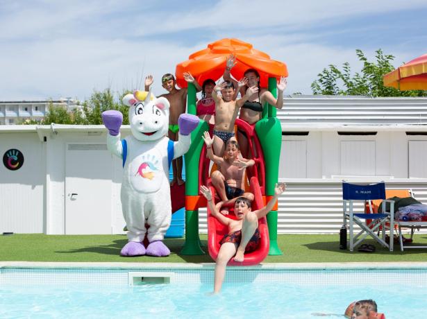 Kids on a slide at the pool with a unicorn mascot.