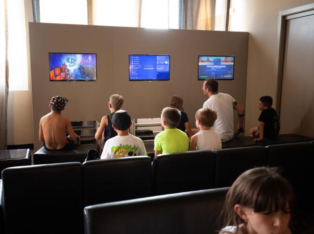 Kids playing video games on screens in a gaming room.